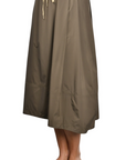 khaki nylon midi skirt with front pleats, drawstring waistband, and hidden side pockets, styled with a black top and woven sandals