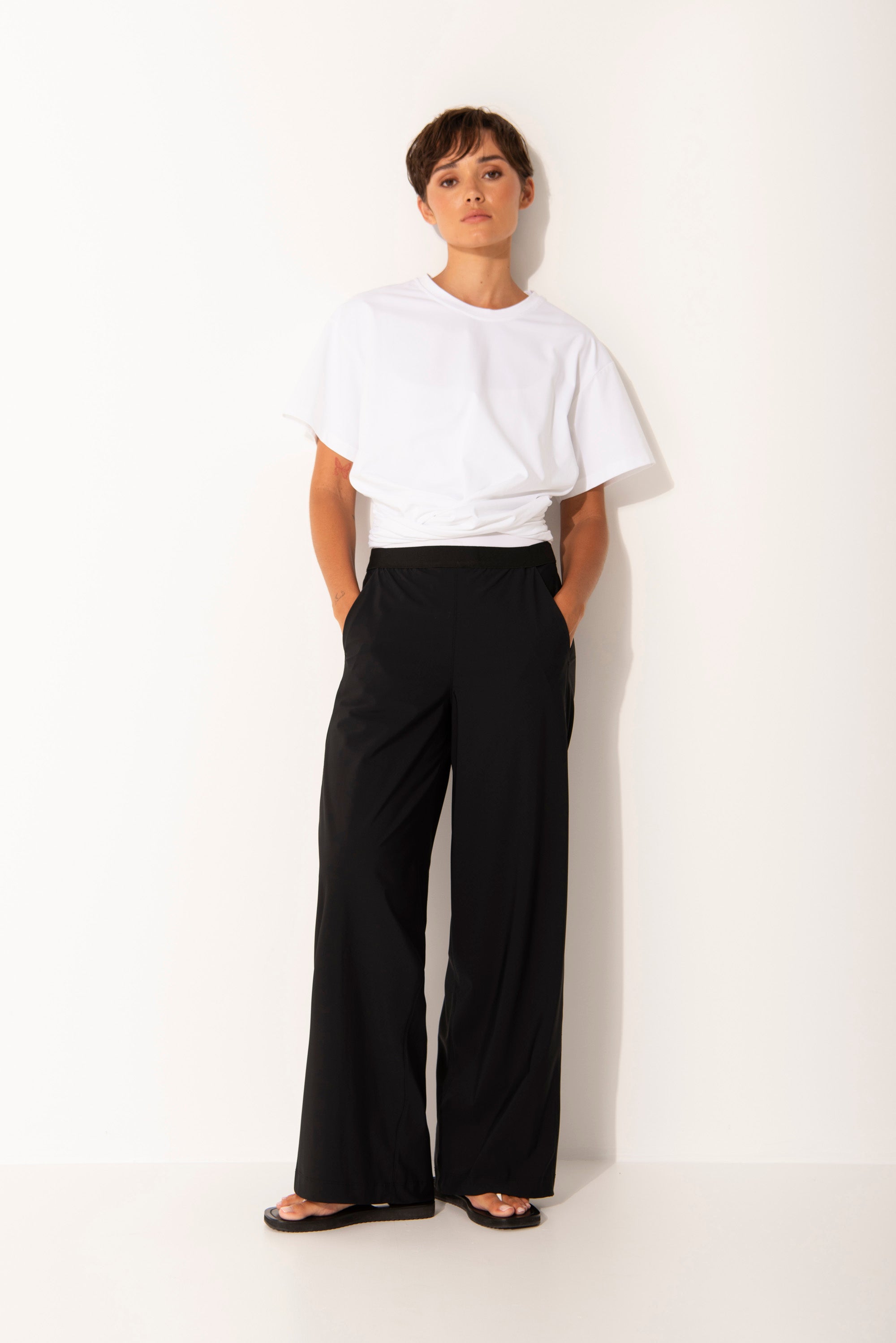 Person wearing a white top and black wide leg pants on a white background